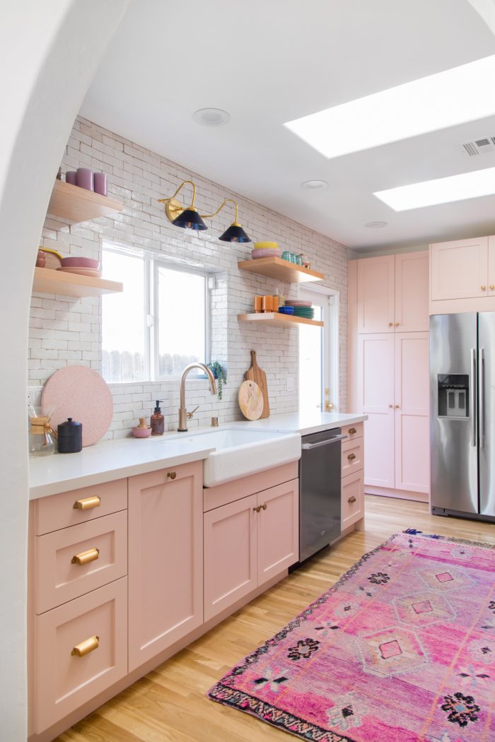 A kitchen with pink cabinets, a sink and a window