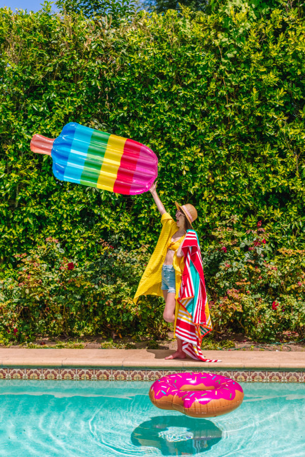 Girl holding a rainbow popsicle floatie