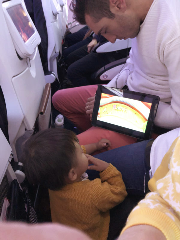 A little kid on a plan with an ipad