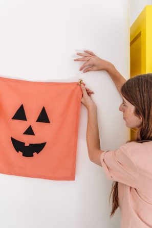 A person holding a sheet that looks like a pumpkin