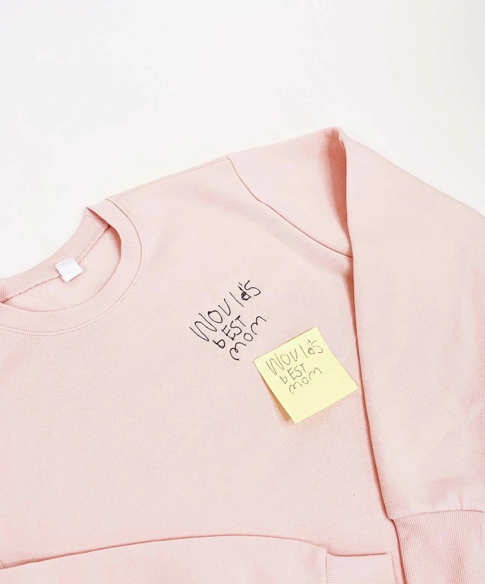 Pink sweatshirt with embroidery and post it note on top