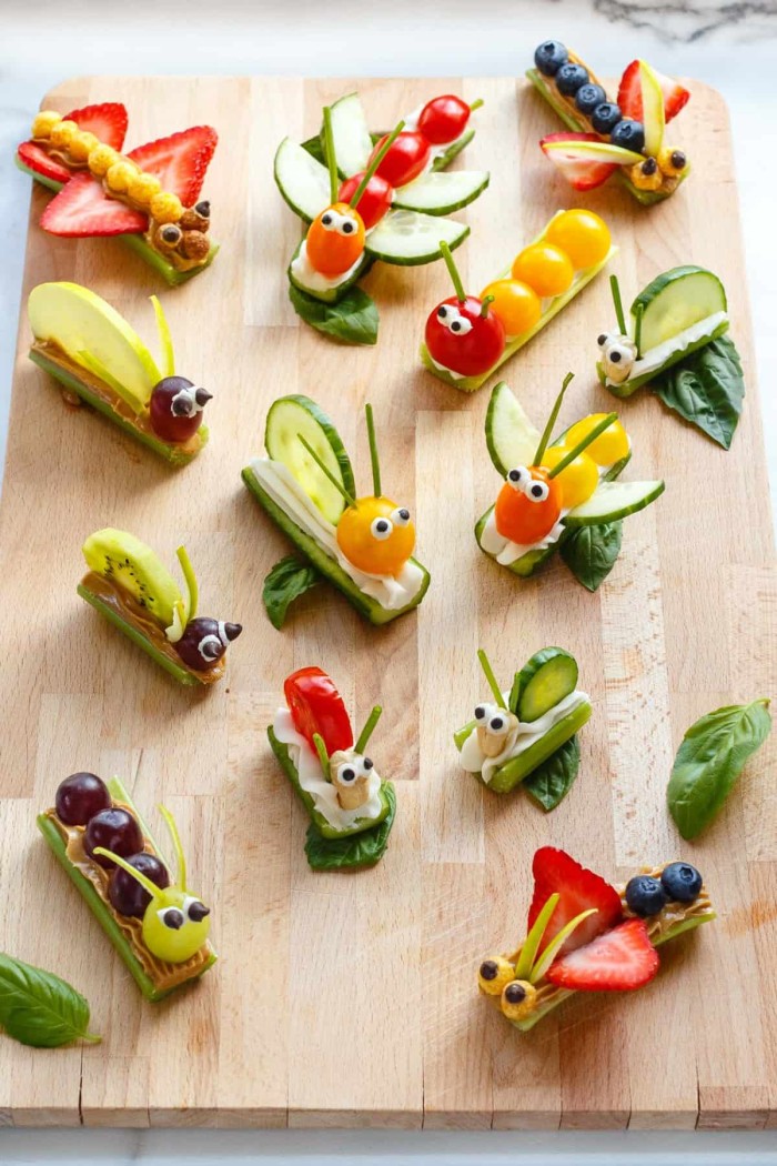 Fruit and vegetable bug snacks on a cutting board.