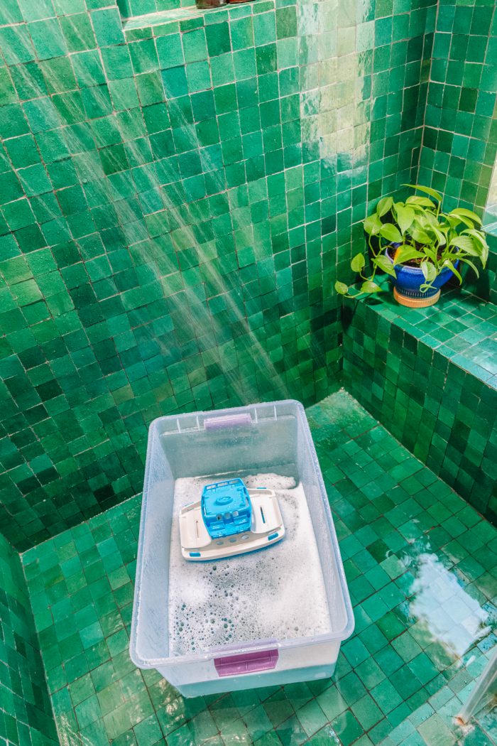 A green tiled shower with a bucket