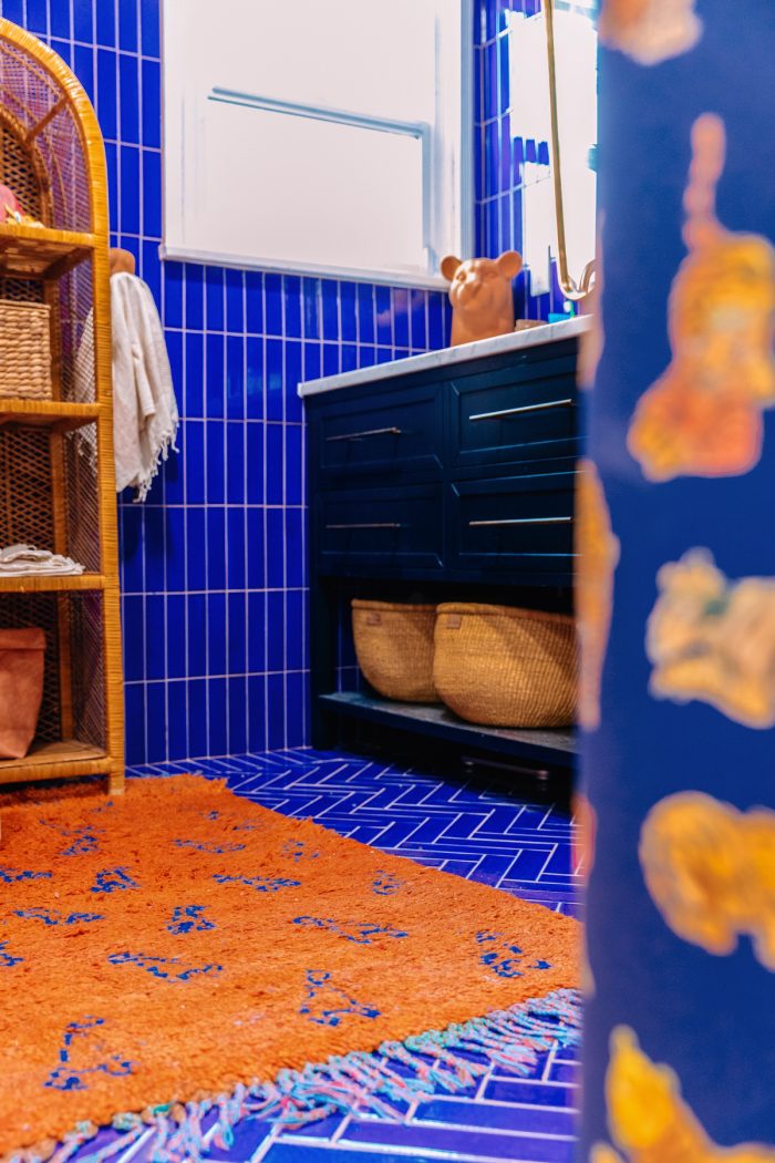 A blue bathroom with an orange rug