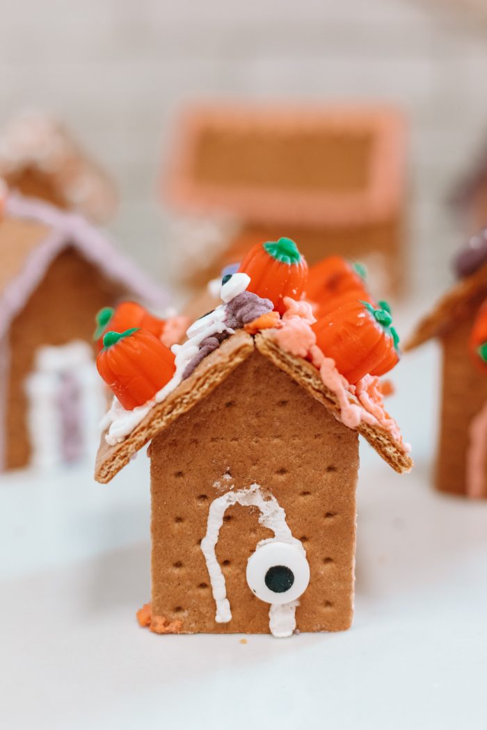 A house made of graham crackers with small pumpkins on the roof