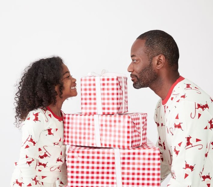 Child and father in christmas pajamas holding presents