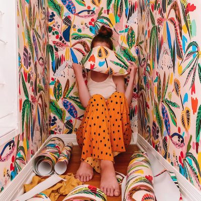 A women in a closet with colorful wallpaper