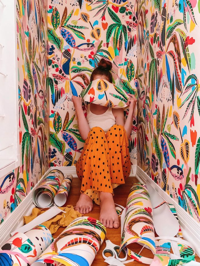 A women in a closet with colorful wallpaper