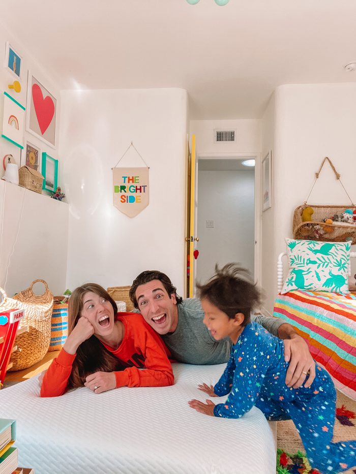 A group of people sitting on a bed laughing