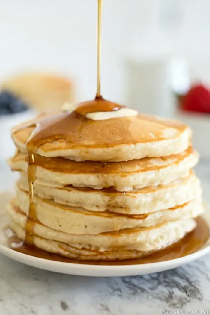 Stack of pancakes with syrup being poured over it