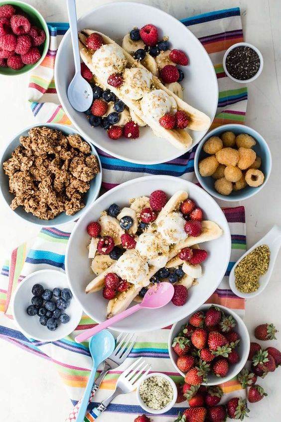 Breakfast Banana Split with bowls of granola and berries on a striped towel