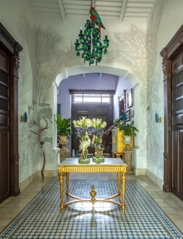 An entrance to a house with a gold table and flowers