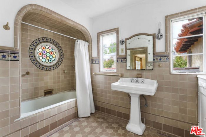 A bathroom room with a sink, a mirror, and a bath