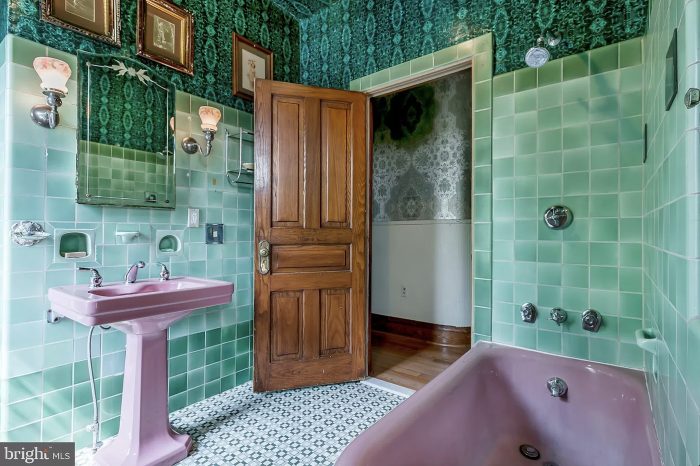 A green bathroom with pink sink and bath tub