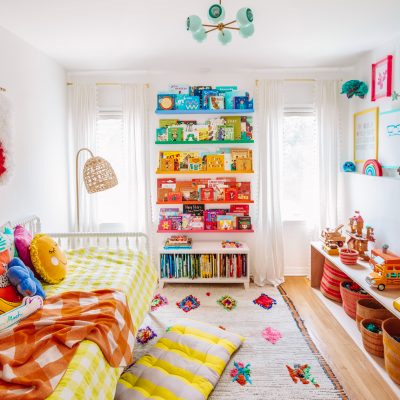 A bedroom with rainbow bookshelves