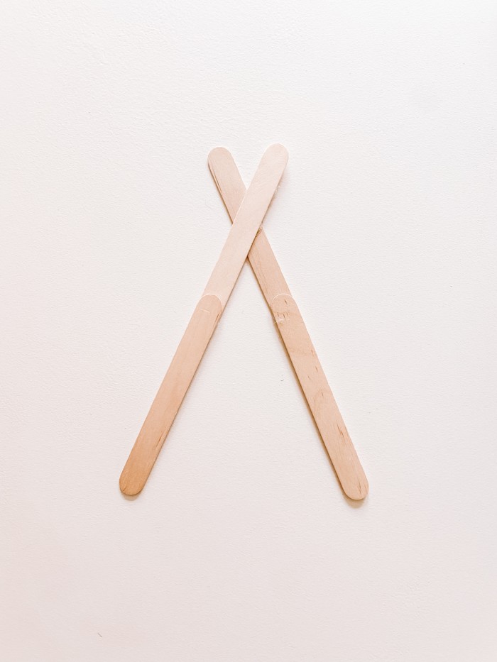 Popsicle sticks glued together and crossed in an X shape on a white table