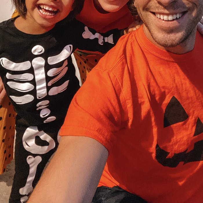 Kid in Halloween Skeleton Pajamas and Dad in Jack-o-Lantern Shirt