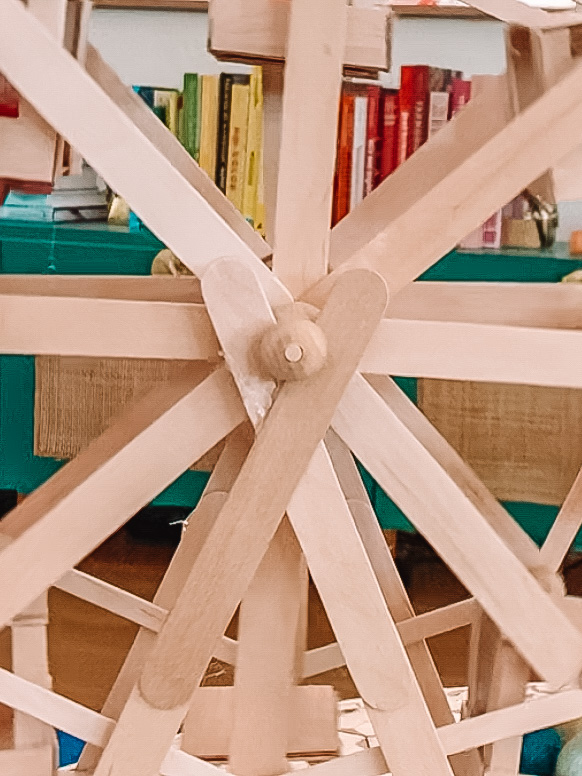 Popsicle stick Ferris wheel with rainbow books behind it
