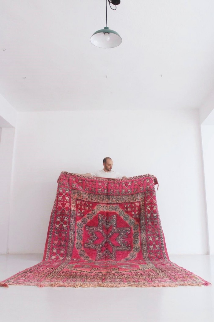 Vintage Fuchsia Moroccan Rug held in front of a white wall