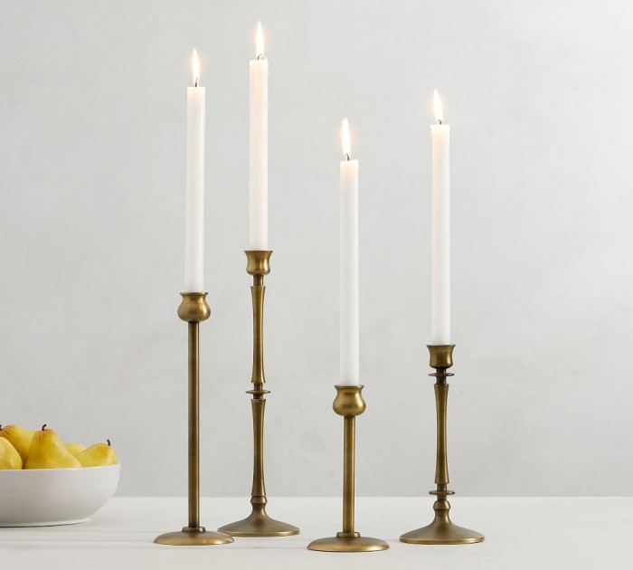 four brass candlesticks on a white table