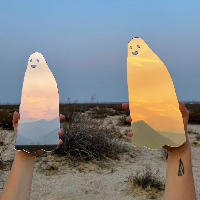 Ghost mirrors held against a sky and desert background