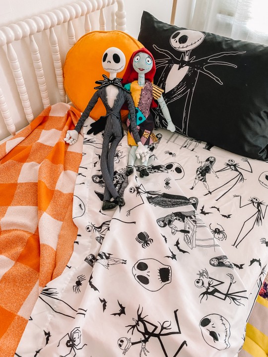 Nightmare before christmas sheets on bed with stuffed animals and plaid blanket