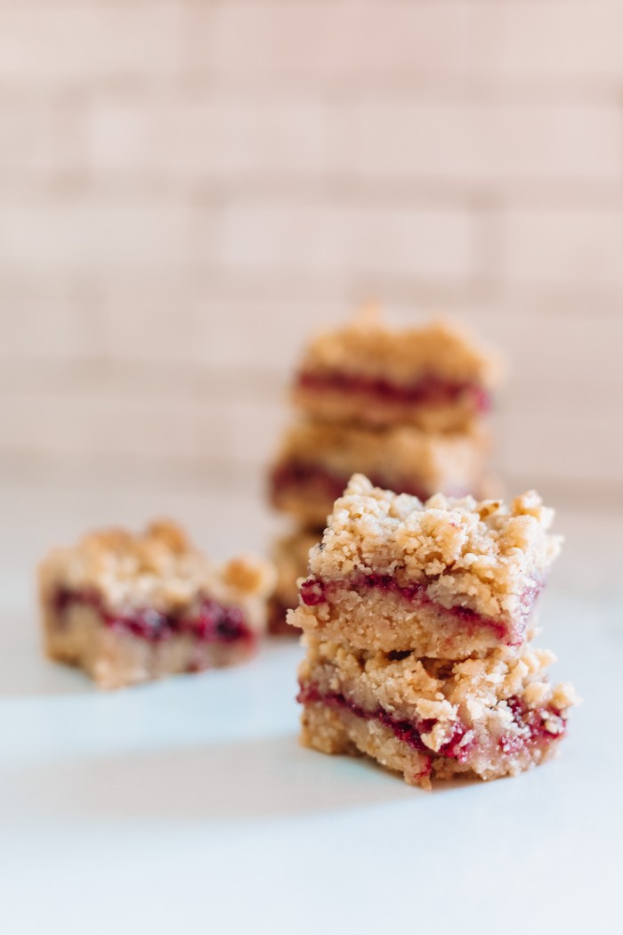 Raspberry Bars stacked in front of white tile