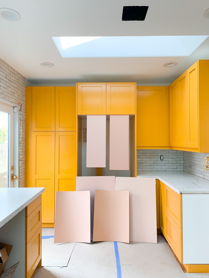 Yellow orange kitchen cabinets with pink paint swatches in front