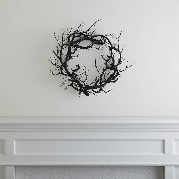 Black branch wreath on a white wall over a white mantle