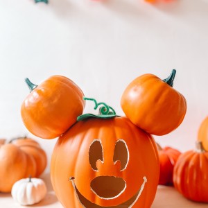 Mickey Mouse pumpkin in front of pumpkins, white wall and pumpkin lights