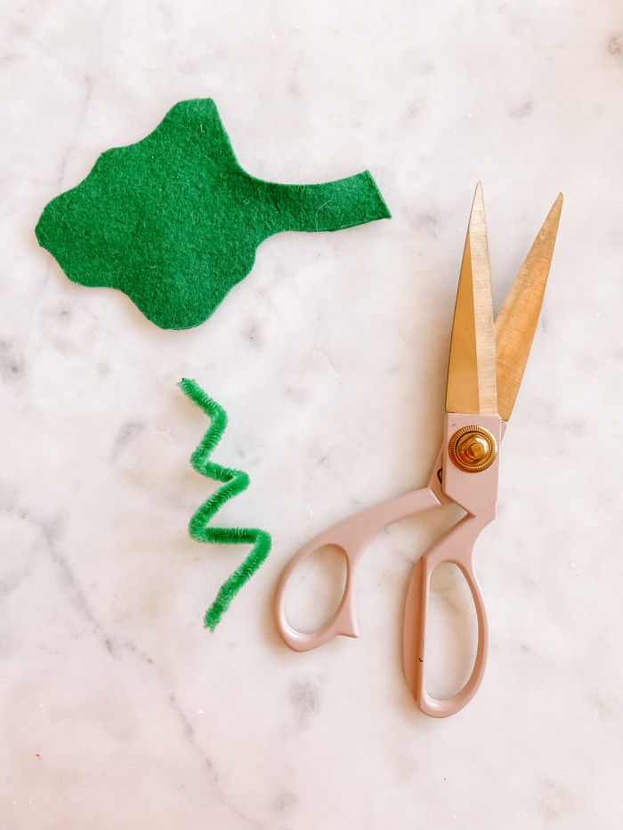 green felt leaf, green pipe cleaner and scissors on marble table