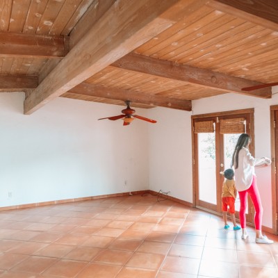 Mom and child in empty house with terracotta floors and wood beamed ceilings