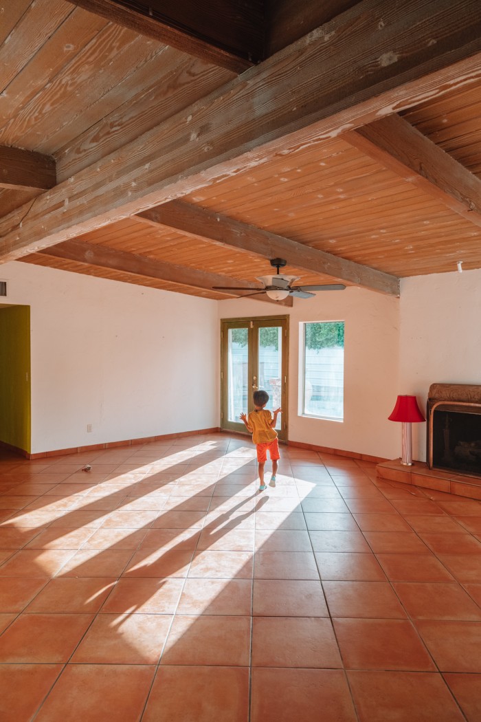Child in empty house with wood beamed ceilings and sunlight