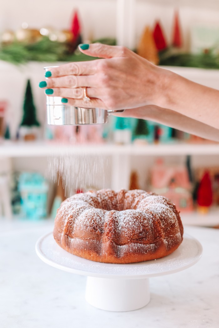 Coffee bundt cake being dusted with powdered sugar