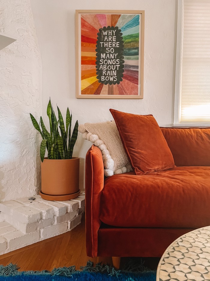 Rust sofa with rainbow art print above it