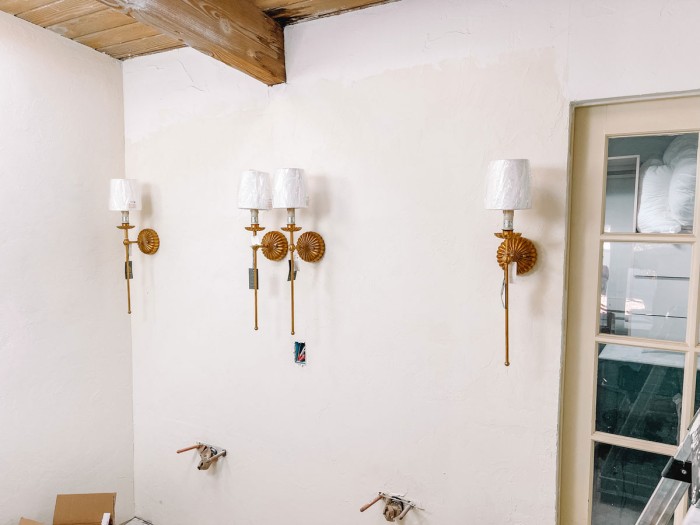 Brass sconces on wall in bathroom under construction