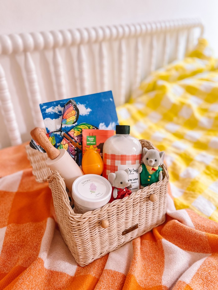 basket filled with items for easter on gingham bed sheet