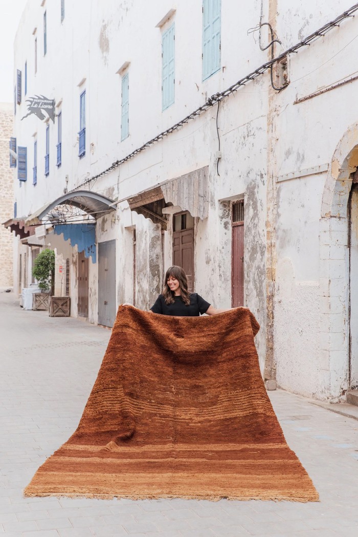 woman holding large cognac brown moroccan rug