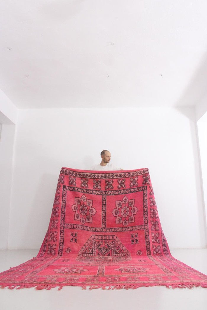 large pink moroccan rug held against a white while