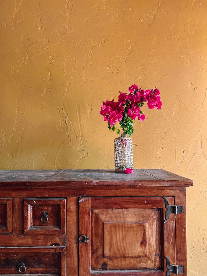 bougainvillea on wood console with ochre walls