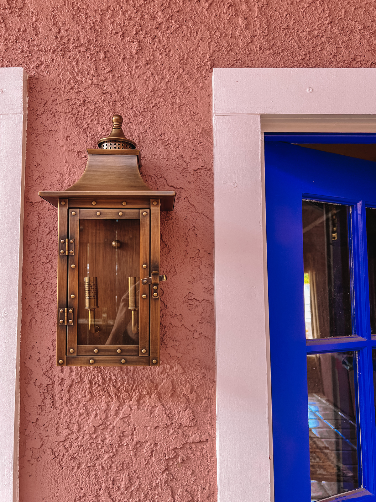 brass exterior lanterns on pink house with blue door