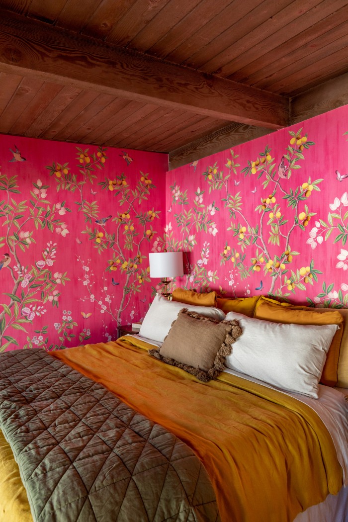 bed with mustard duvet and cream pillows with chinoiserie wallpaper behind