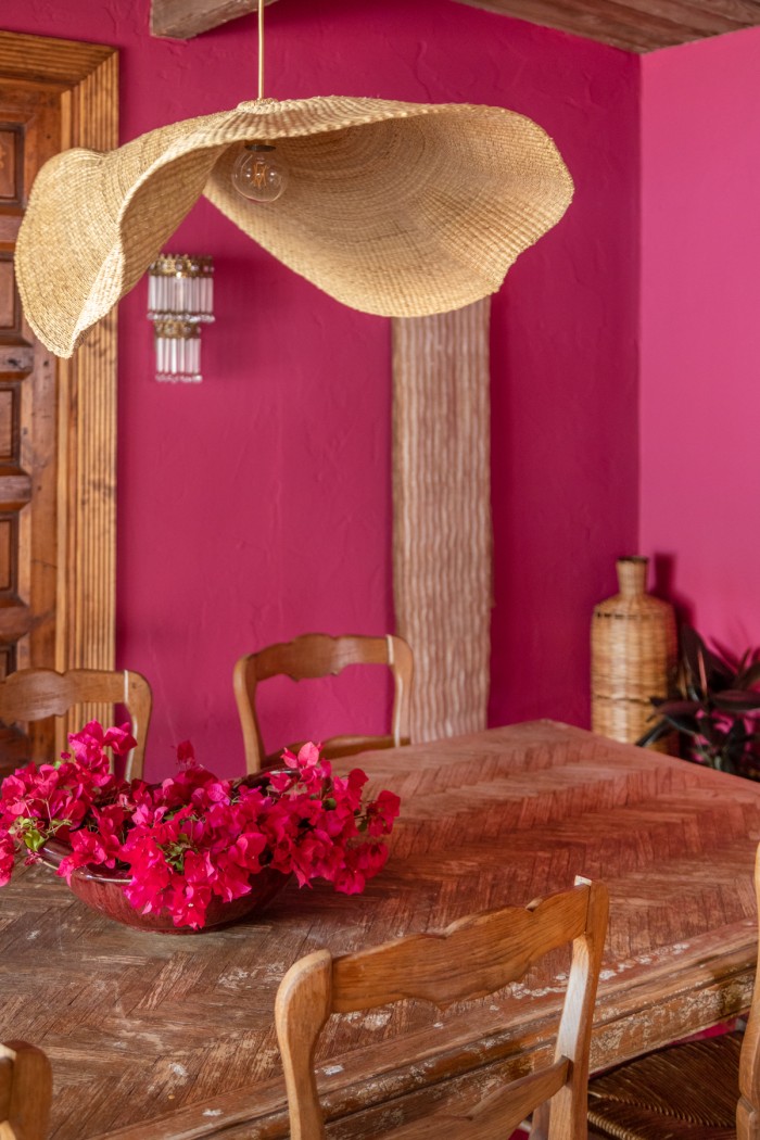 table with bougainvillea on it and rattan chandelier in pink room