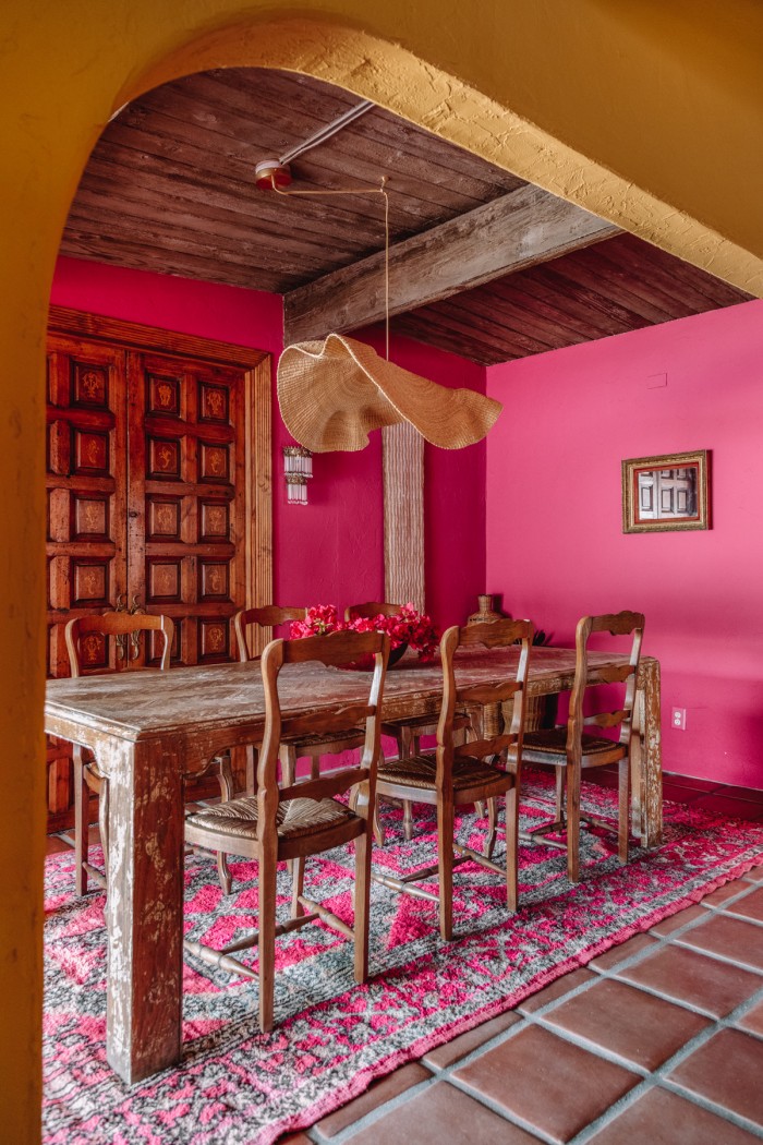 pink dining room with wood table and arch