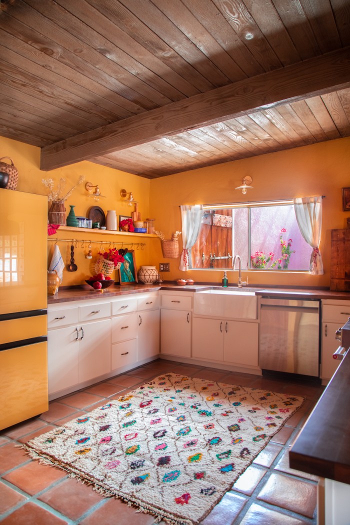 yellow kitchen with multicolor rug on terracotta floor