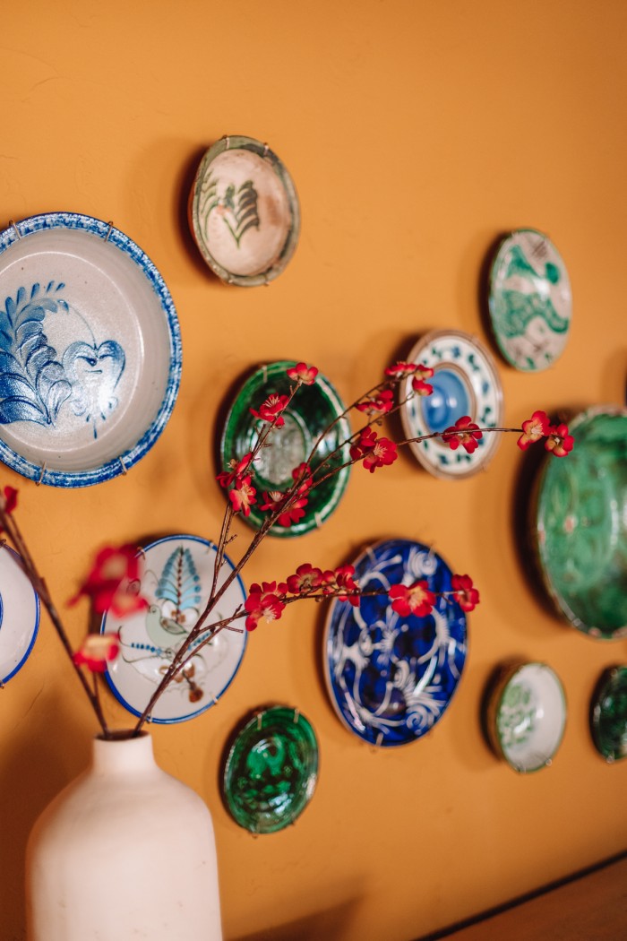 green and blue plates hanging on wall with red flowers
