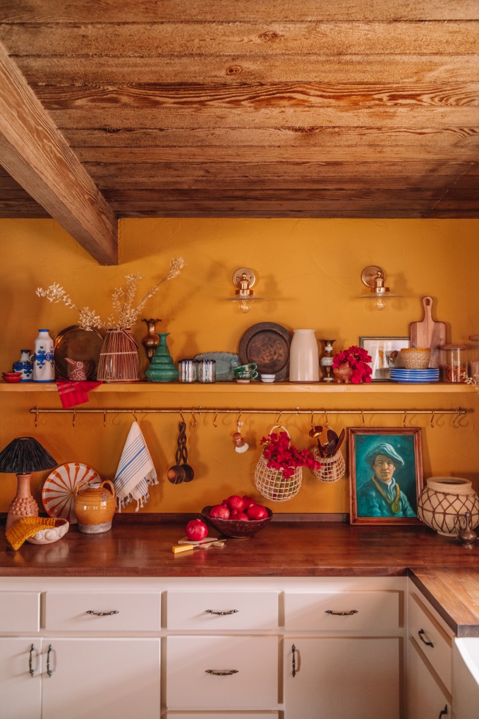 ochre yellow kitchen walls with shelf and brass pot rail