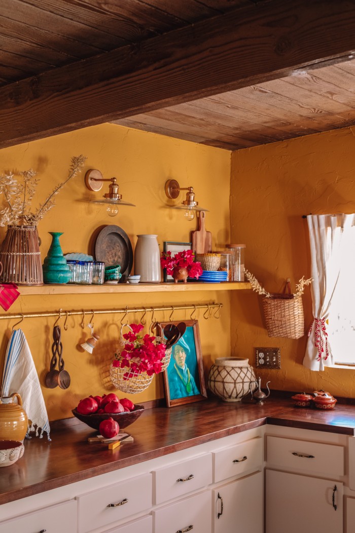 yellow kitchen with wood ceiling and shelf with colorful decor and dishes