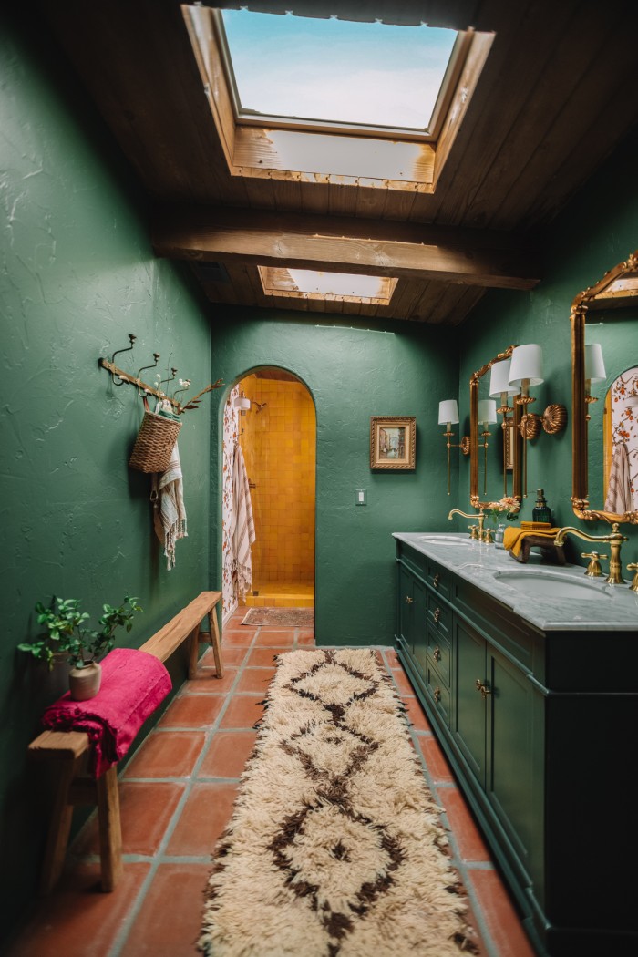 dark green bathroom with skylights and archway to yellow shower