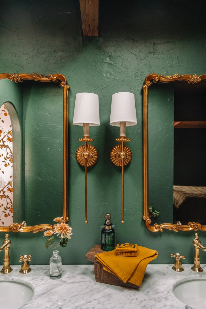 brass sconces in green bathroom